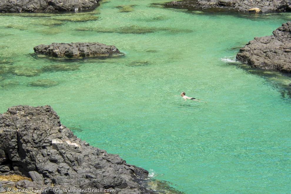 Imagem de um moço nadando no mar azulado da Baía dos Porcos.